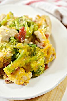 a white plate topped with broccoli covered in cheese and chicken mixtures next to a fork