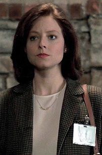 a woman standing in front of a brick wall with a name tag on her jacket