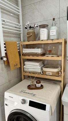 a washer sitting next to a dryer in a bathroom under a towel rack