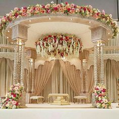 a wedding stage decorated with flowers and chandelier for the bride's ceremony