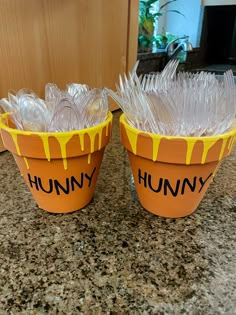 two plastic buckets sitting on top of a counter covered in plastic wrap and frosting