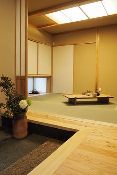 an empty room with wooden floors and white flowers in a vase on the floor next to it