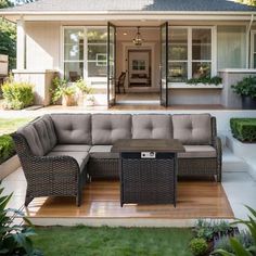 an outdoor living area with couches, tables and potted plants in front of the house