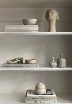 three white shelves with books and vases on them