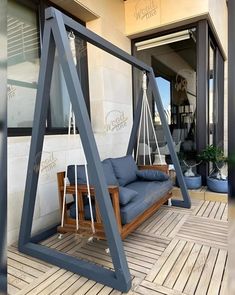 a swing chair sitting on top of a wooden floor next to a building with windows