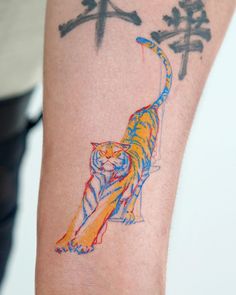 a colorful tiger tattoo on the arm of a person with chinese characters in the background