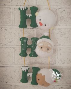 christmas ornaments hanging on a brick wall in the shape of letters and santa claus's hat