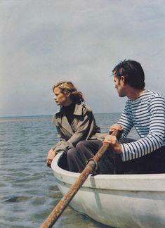 a man and woman in a boat on the water with a long wooden oar