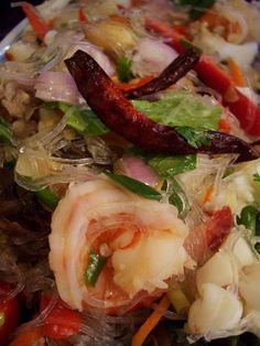 a salad with shrimp, carrots, and other vegetables in it on a plate