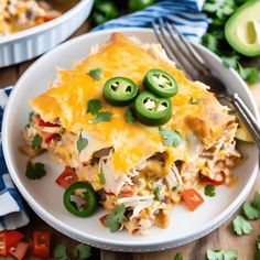 a white plate topped with a layered enchilada covered in cheese and jalapenos