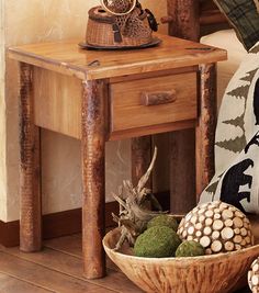 a wooden table sitting next to a basket filled with pine cones and other decorative items