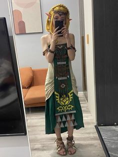 a woman taking a selfie in front of a mirror wearing sandals and a green dress