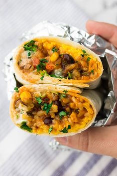 two burritos sitting on top of foil with the words delicious vegan burritos