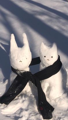 two snowmen with black scarves and scarfs on their heads in the snow