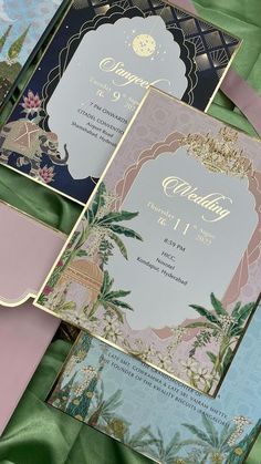 three different types of wedding cards on top of a green cloth covered tablecloth with pink, blue and gold trimmings