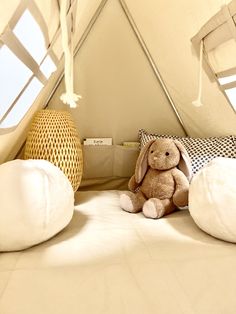 a stuffed animal sitting on top of a bed in a room with white walls and windows