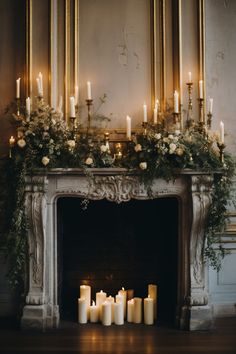 a fireplace with candles and flowers on it