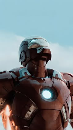 an iron man standing in the sky with his arms outstretched and glowing light on it's chest