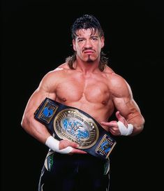 a man holding a wrestling belt in his right hand and pointing at the camera with both hands