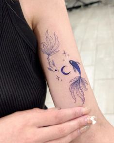 a woman's arm with a tattoo on it that has a fish and moon