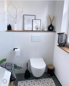 a white toilet sitting in a bathroom next to a window and rug on the floor