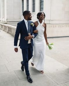 a man and woman are walking down the street holding flowers in their hands as they smile