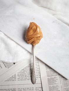 a spoon with peanut butter on it sitting on top of some papers and paper towels