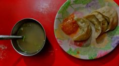 a plate with some food on it next to a bowl of soup and spoons