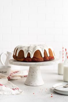 a bundt cake sitting on top of a white cake plate next to milk bottles