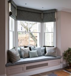 a window seat with pillows on it in front of a potted plant and windowsill