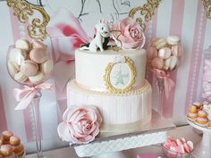 there is a white cake with pink flowers on the top and gold trimmings