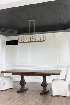 a dining room table with chairs and a chandelier hanging from it's ceiling