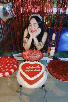 a woman sitting in front of two heart shaped cakes