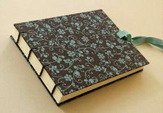 an open book with a blue ribbon tied around the front and back cover, sitting on a white surface