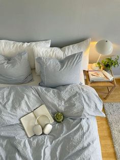 a bed with blue and white striped comforter on top of it next to a night stand