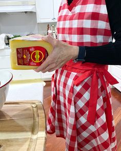 a woman in an apron holding a bottle of mustard