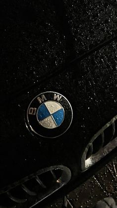 the front grill and emblem of a bmw car in the dark with snow on it