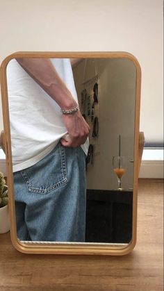 a person standing in front of a mirror with their hand on the back of his pants