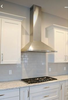 a stove top oven sitting inside of a kitchen next to white cupboards and drawers