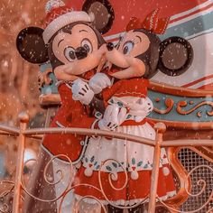 two mickey and minnie mouses kissing on a disney world ride in the winter snow