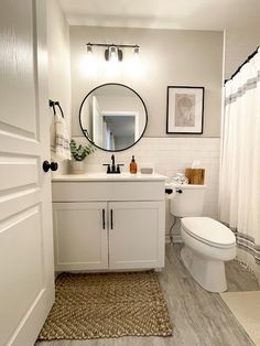 a bathroom with a toilet, sink, mirror and shower curtain in it's corner