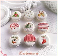 twelve decorated cupcakes are displayed on a white tablecloth with red trimming