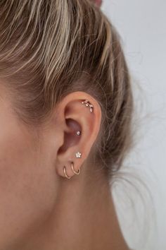 a close up of a woman's ear with two piercings on it and one behind her ear