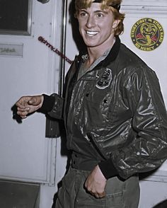 a man in an air force pilot's uniform is smiling and pointing to the side