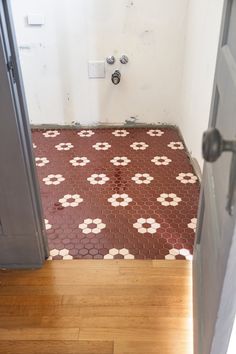 an open door leading to a bathroom with red and white floor tiles on the floor