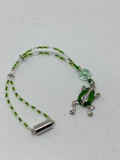 a green and white beaded lanyard with a frog on it's side