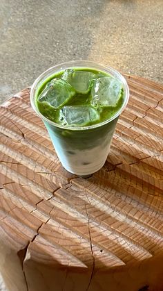 a drink with ice and green liquid on a wooden table