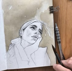 a pencil drawing of a woman with her hand on her face, next to a pair of scissors