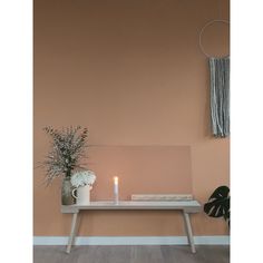 a table with a candle and some flowers on it in front of a pink wall