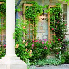 a house covered in vines and flowers next to a light pole with a lamp on it